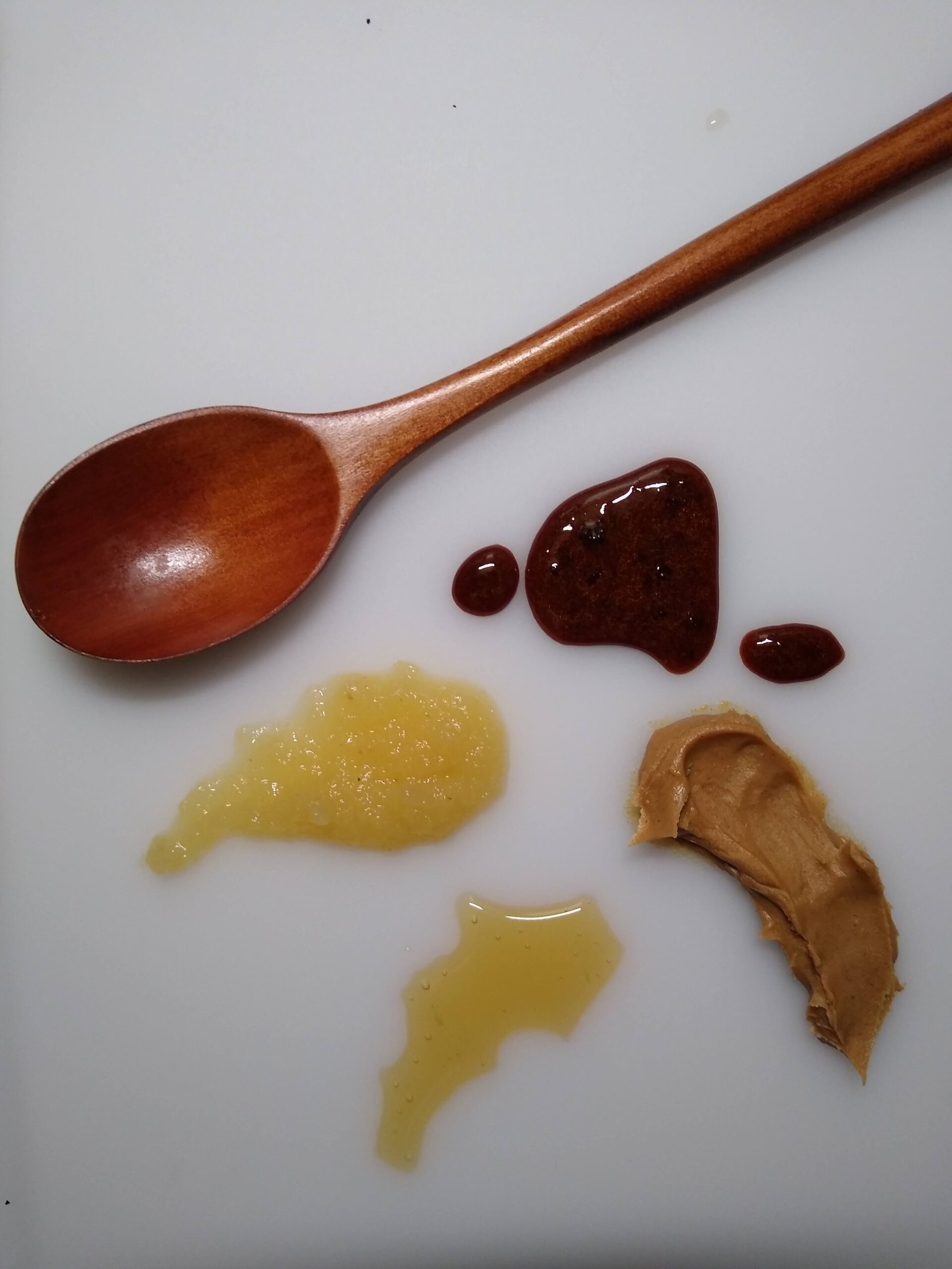 Smears for horse lick mat and spoon on a white surface, including applesauce, honey, peanut butter, and molasses