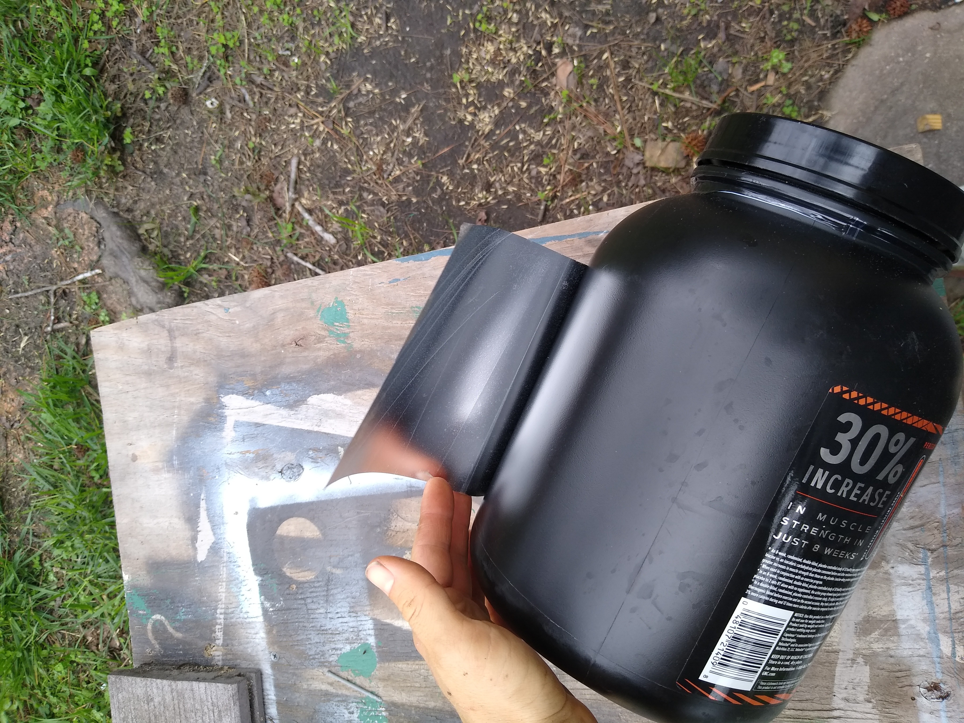 Removing label from black plastic canister. 