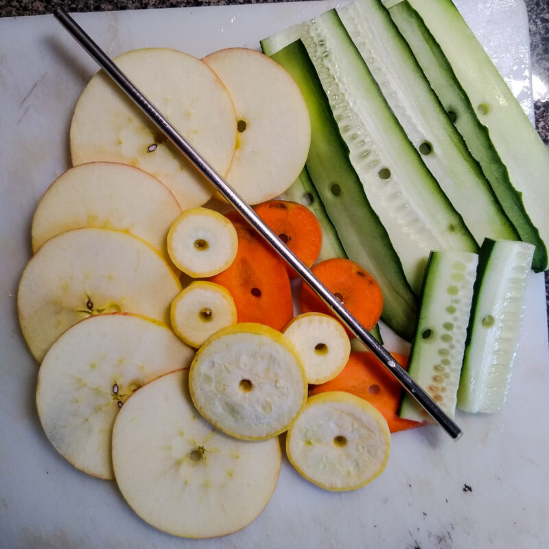 Set of veggie and fruit slices with perfect holes in center. Stainless steel straw on top. 
