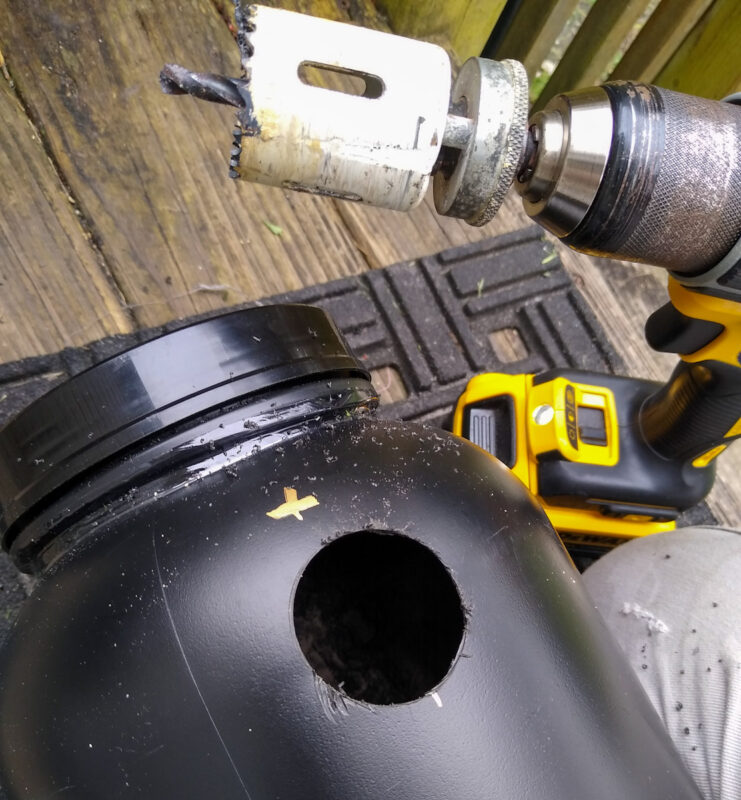 Close up of hole saw and hole in plastic canister.