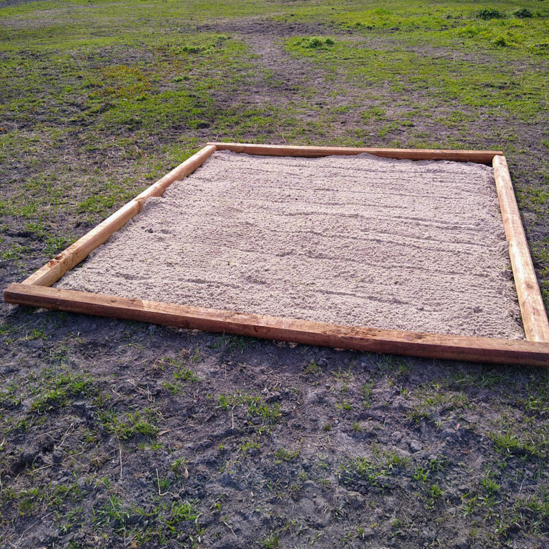 A DIY sand station for horses made of clean sand in a square shape with timber frame.
