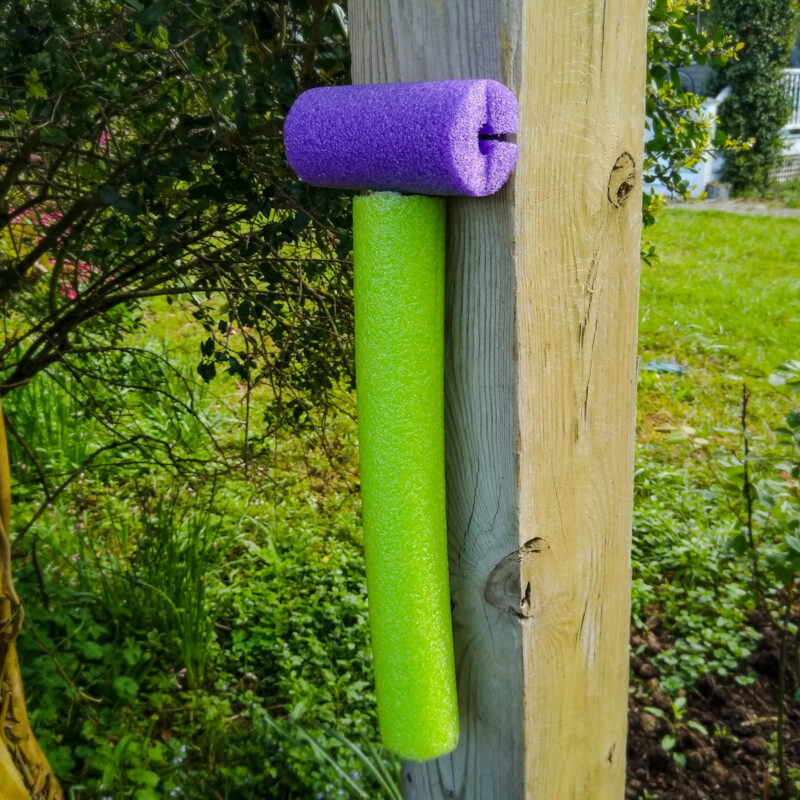 A wooden gatepost with exposed eyebolt covered in pool noodle.