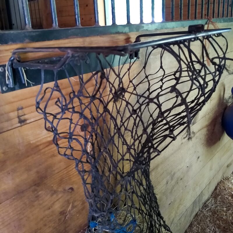 A horse hay net in a metal frame for easy filling.