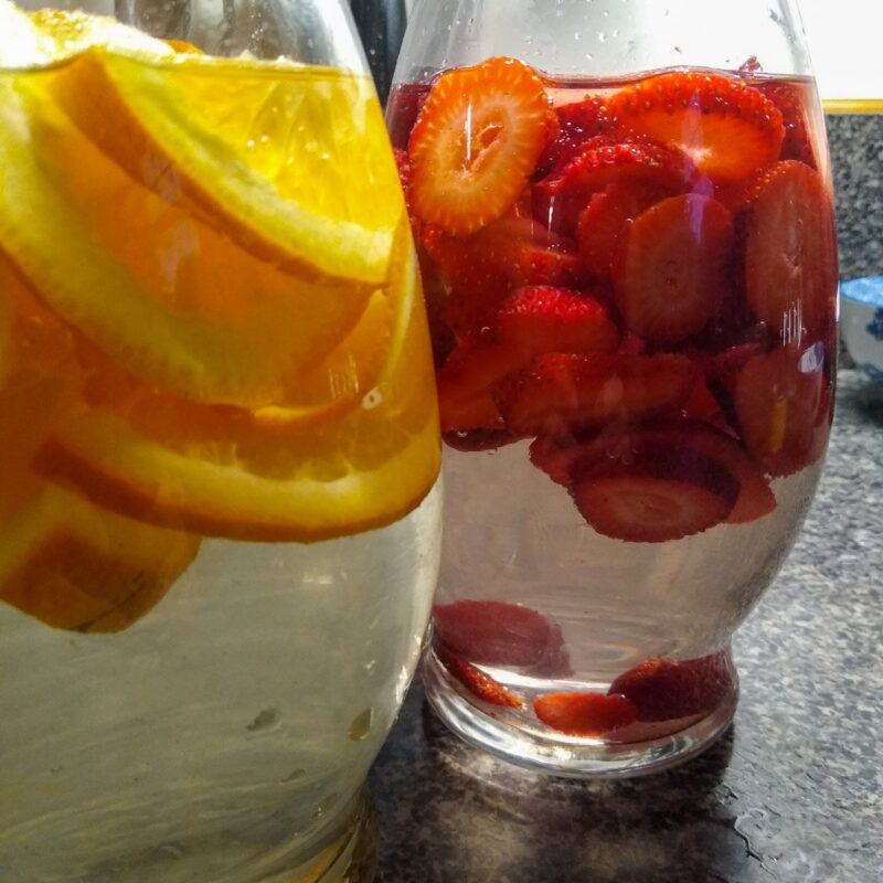 Fruit flavored water for horses. To left, orange flavored water. On right, water flavored with fresh strawberries.