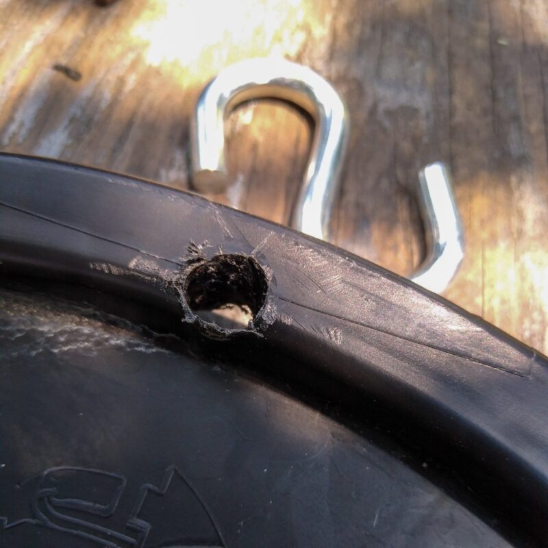 Close up of black bucket lid with hole drilled and steel S hook ready to attach to the DIY horse toy