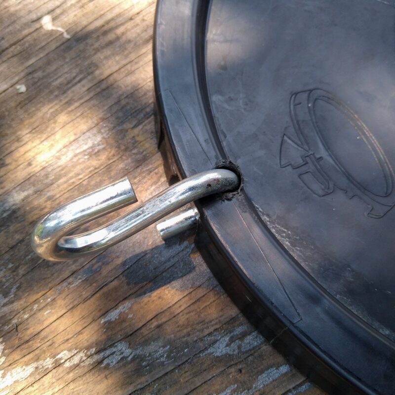 Close up of bucket lid with S hook attached to hole in rim of lid