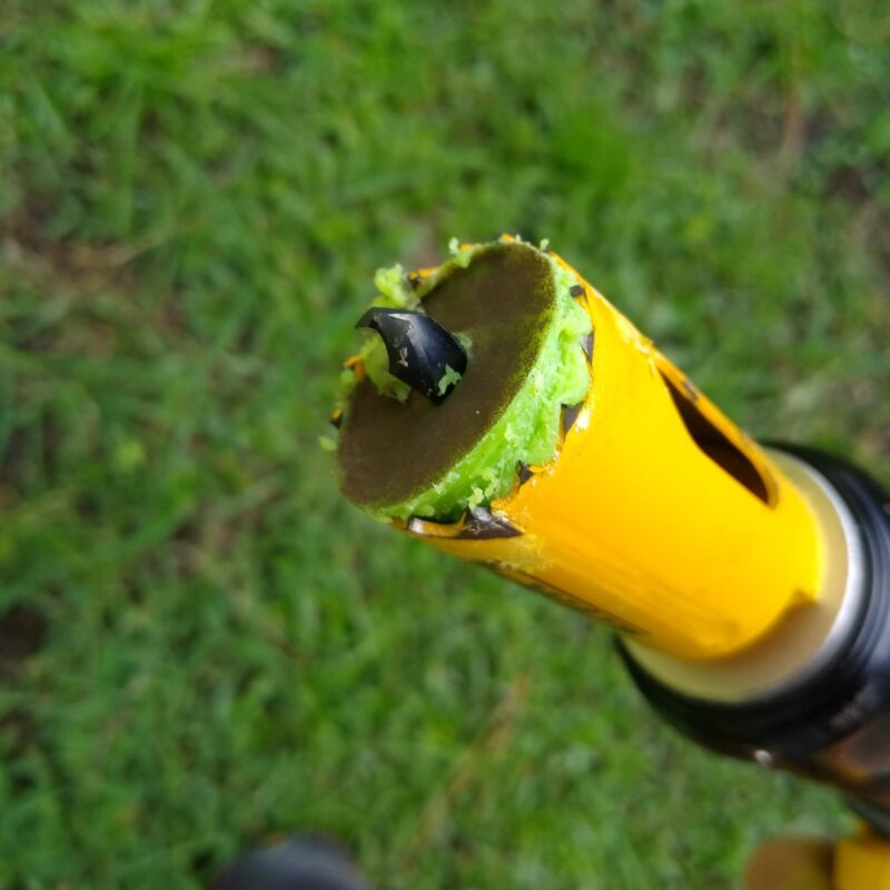 Close up of yellow DeWalt hole saw with green rubber chunk in the saw.