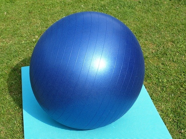 A large blue yoga ball on a grassy background.