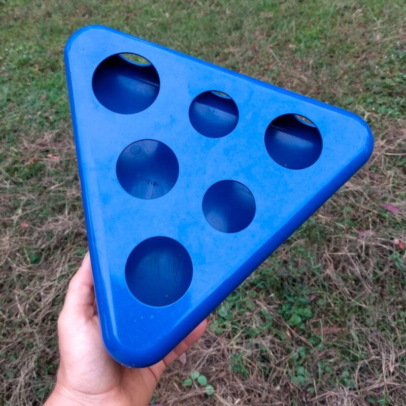 A blue plastic triangle shaped cat toy with six holes to be repurposed into the swinging hay toy.