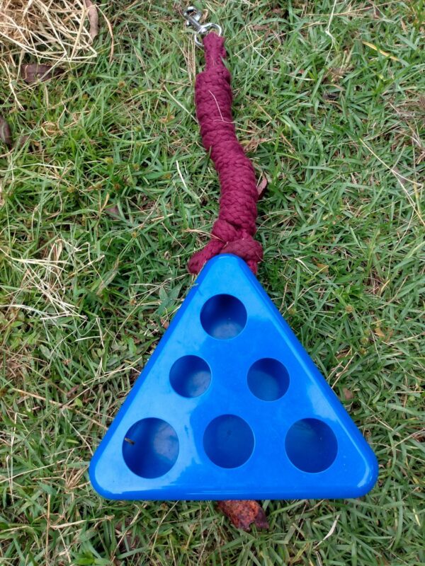 The DIY swinging hay toy on the ground with attached lead rope, empty and ready for horse treats.