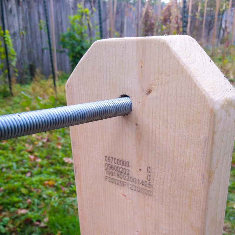 Close up of a piece of lumber with rounded corners. A metal threaded rod passes through a hole in the center of the lumber.
