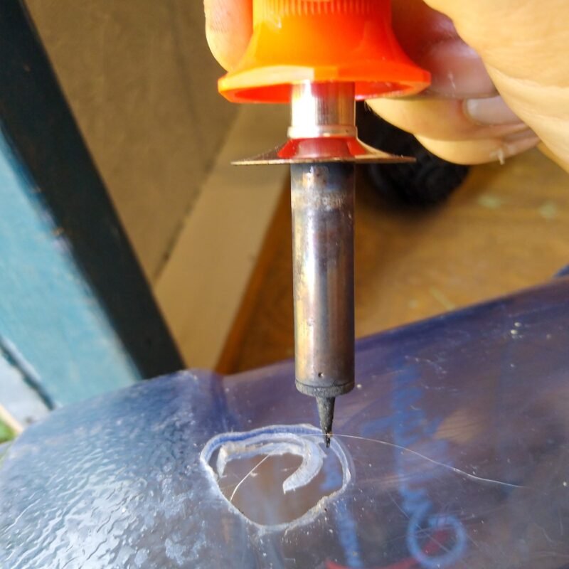 A woodburning tool melts a hole in the bottle for the rod to pass through.