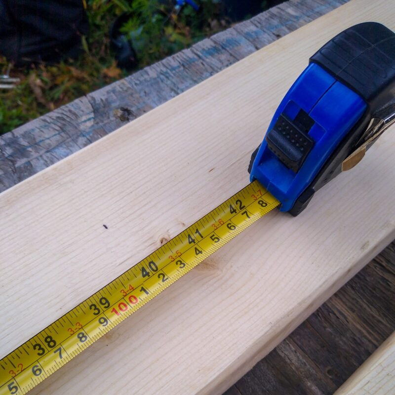A blue tape measure on a piece of lumber.