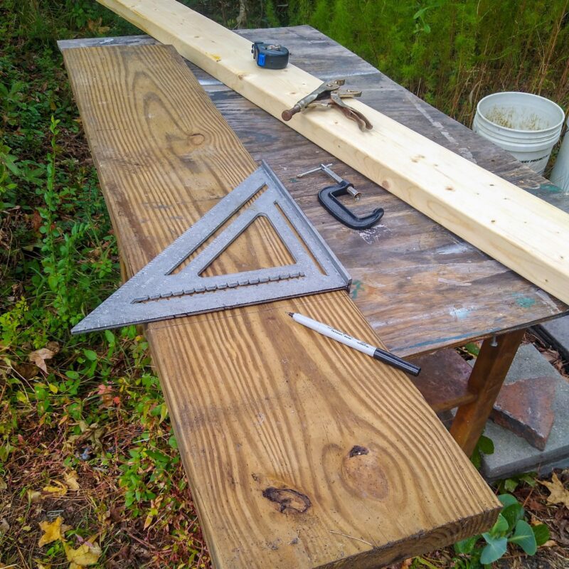 A work table with two pieces of lumber, clamps, and a carpenter's square.