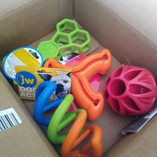 A cardboard shipping box with pile of dog toys inside. 