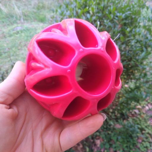 A red JW Pets Megalast dog toy held in a person's hand.