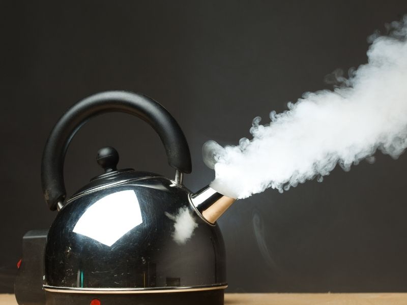 Electric kettle with jet of steam coming from spout