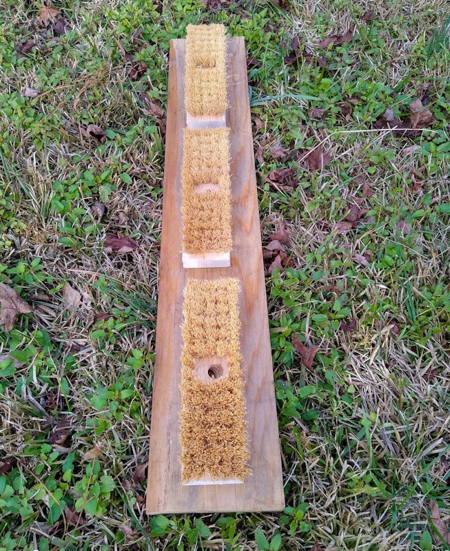 Three scrub brushes on a hardwood board. 