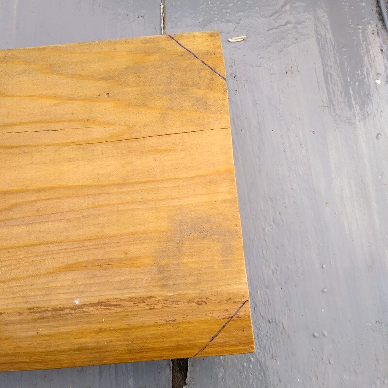 End of wooden board showing corners marked for cutting