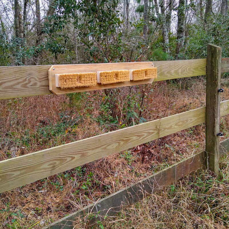 DIY horse scratching board installed horizontally on a wood fence board.