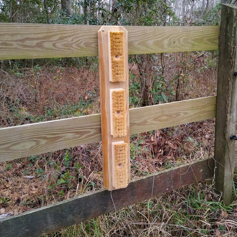 Horse scratching board mounted vertically on a pasture fence