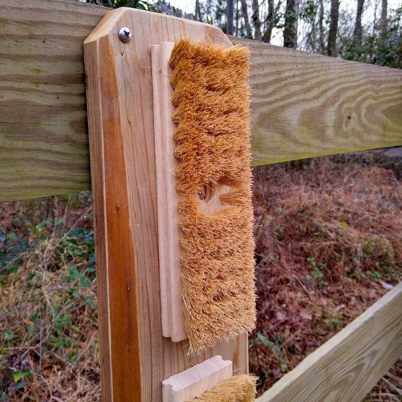 DIY horse scratching board shown close up on a wood fence.