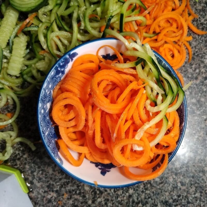 A bowl of fresh carrot noodles and cucumber noodles.