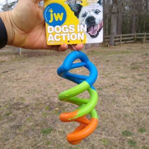The JW Pets Dogs in Action toy held in hand next to a horse pasture