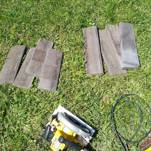 Lengths of composite wood and circular saw lying on grass.