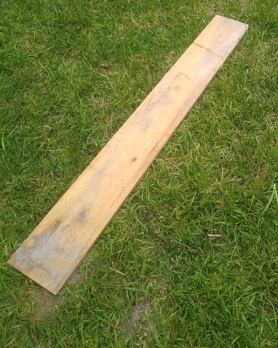 A pine board lying on grass.