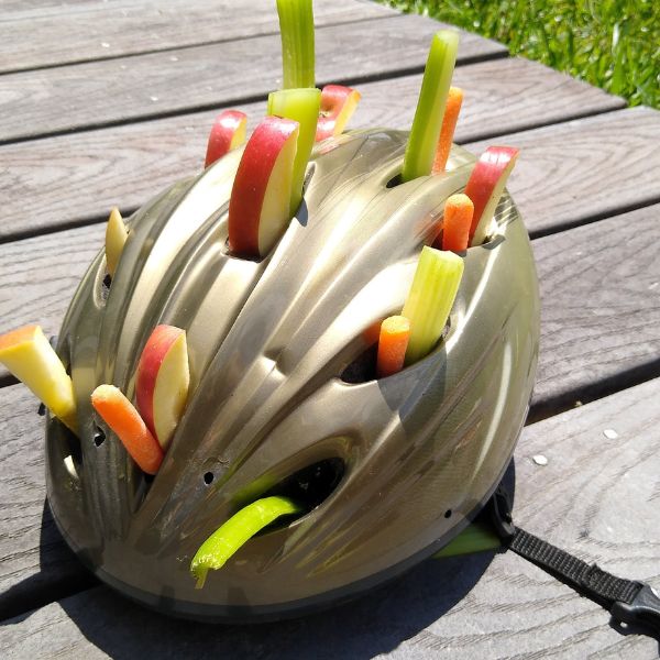 A used riding helmet turned into a horse toy by adding apples, celery, and carrots to the vent holes. 