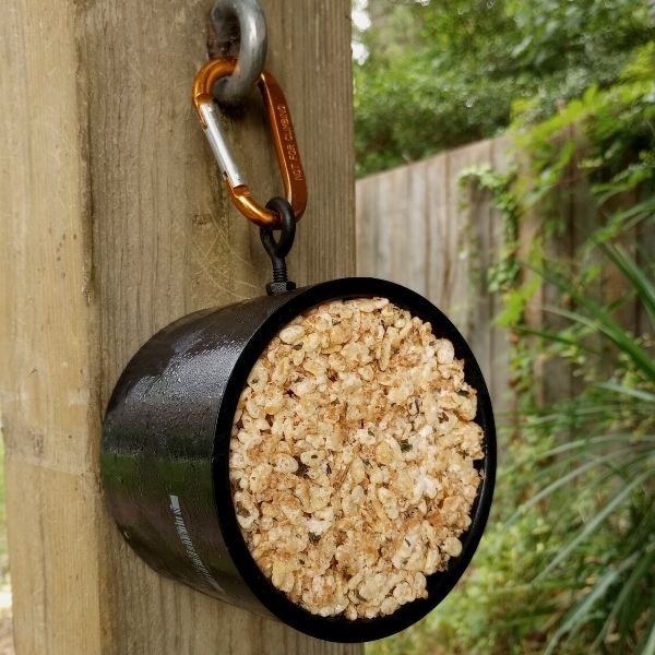 A DIY stall snack licking treat for horses hanging from a wooden post. 