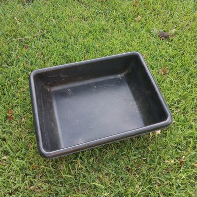Black plastic cement mixing tray used for equine enrichment and feed