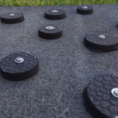 A close up of rubber circle pieces bolted onto rubber mat