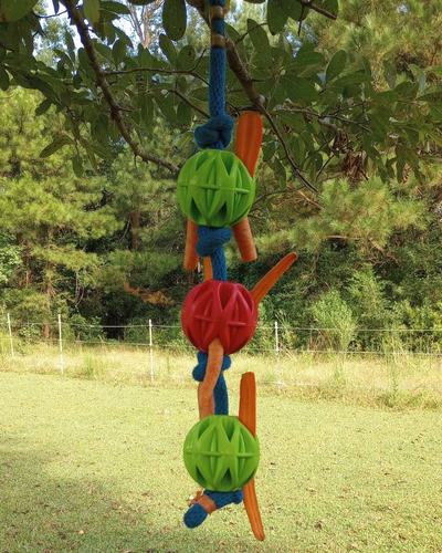 The finished swinging snack toy for horses seen against a green leafy pasture background. 