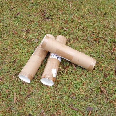 Three cardboard shipping tubes in a pile on grass background.