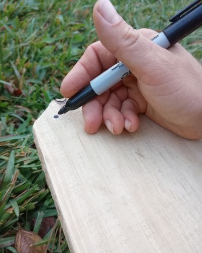 Close up of hand using a Sharpie felt tip pen to mark pilot holes.