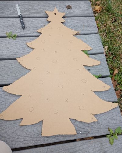 The DIY holiday tree enrichment for horses on a walkway showing marks all over the tree for cutting holes.