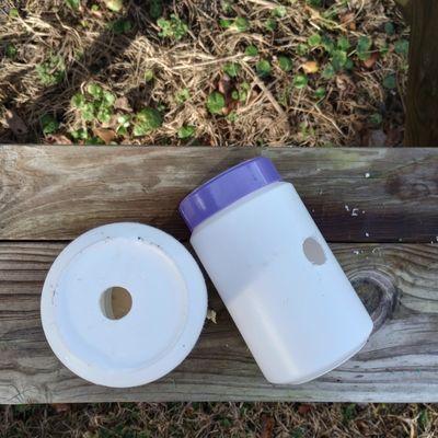 Two white  canisters with purple lid on wood background, each with hole.
