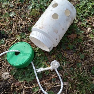 DIY horse toy canister or plastic jar with several holes and rope coming out of lid.