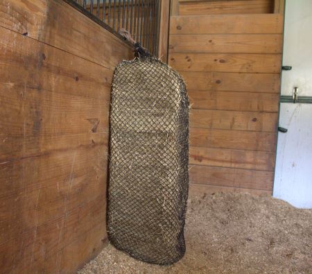 Full bale hay net clipped into a horse's stall. 