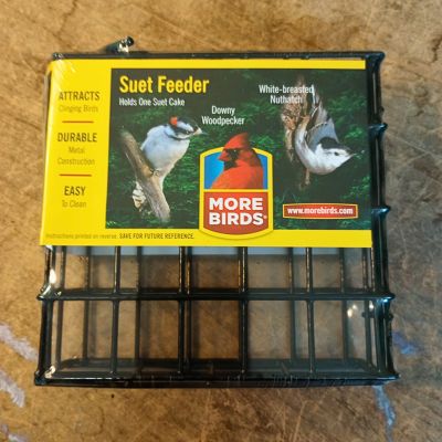 A small suet cage for birds still in packaging against wood background. 