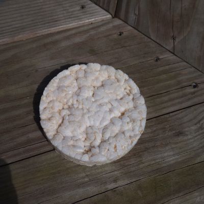 A close up of a plain round rice cake against wood background.
